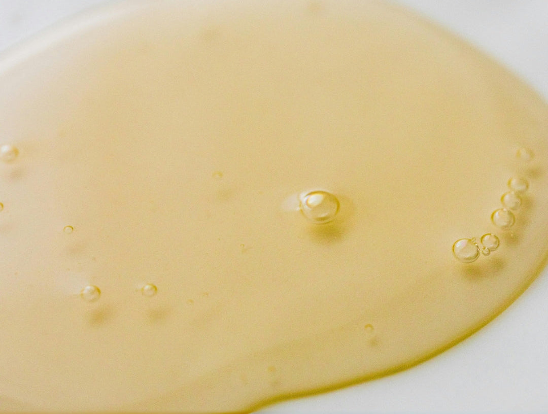 Close-up of a yellowish liquid with bubbles on a white background